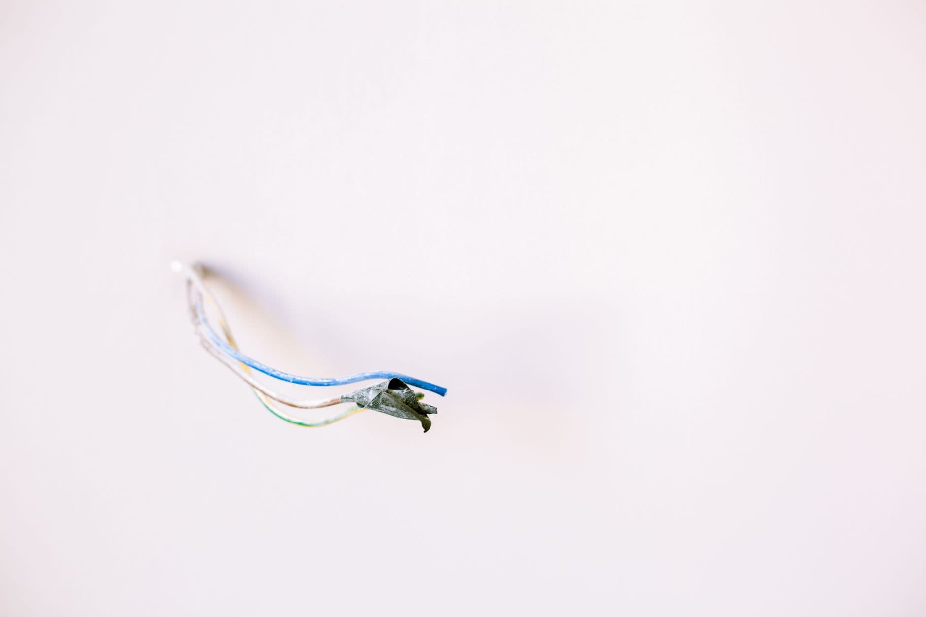 Losse elektriciteitsdraden steken uit een witte muur, klaar om aangesloten te worden
