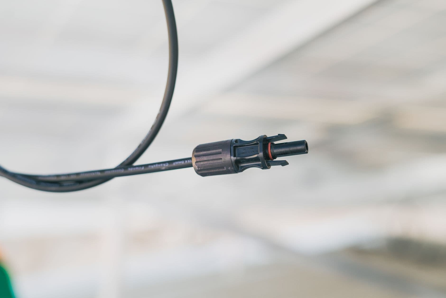 Close-up van een zonnepaneelkabel met stekkerconnector tegen een onscherpe achtergrond