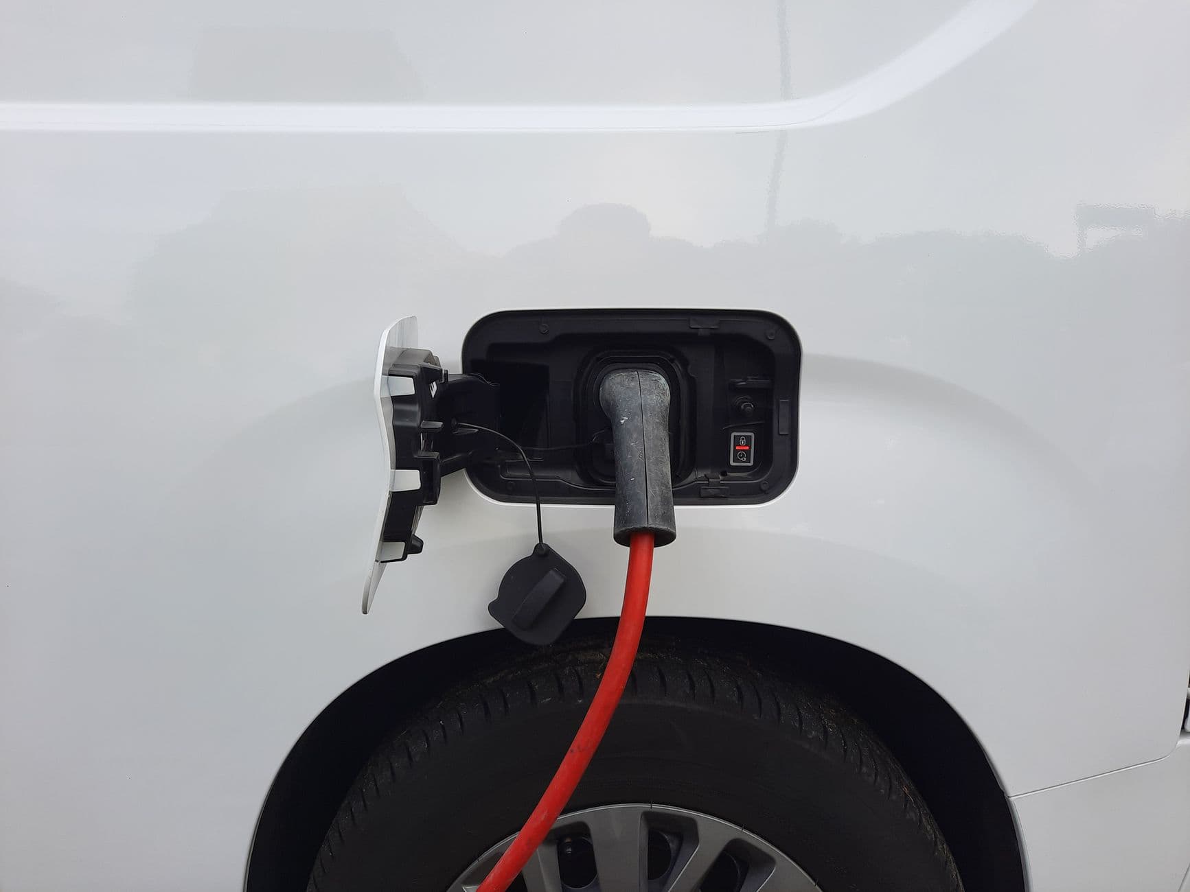Laadkabel aangesloten op de laadpoort van een witte elektrische wagen