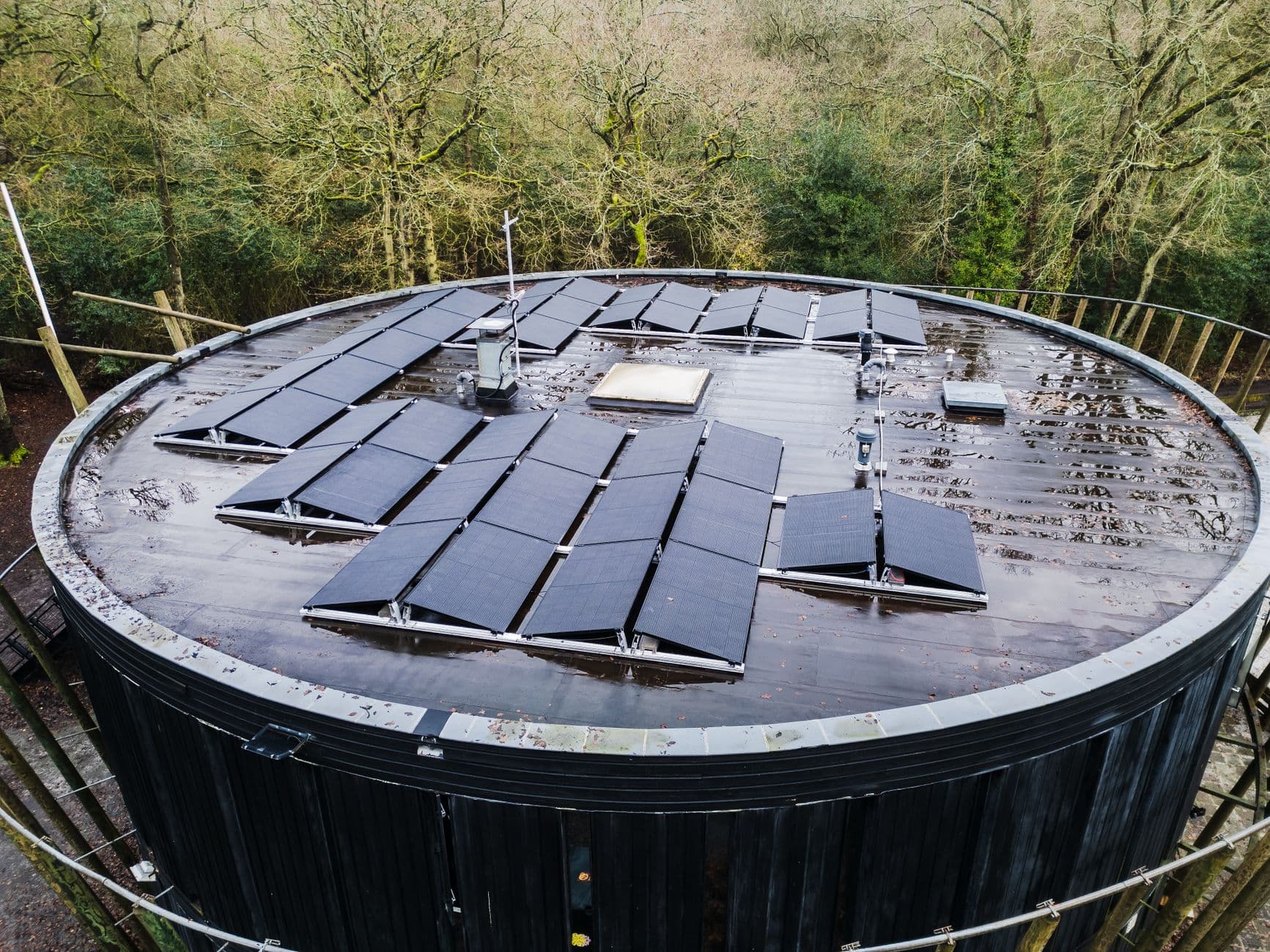 Zonnepanelen op een rond plat dak tussen de bomen, van bovenaf gezien