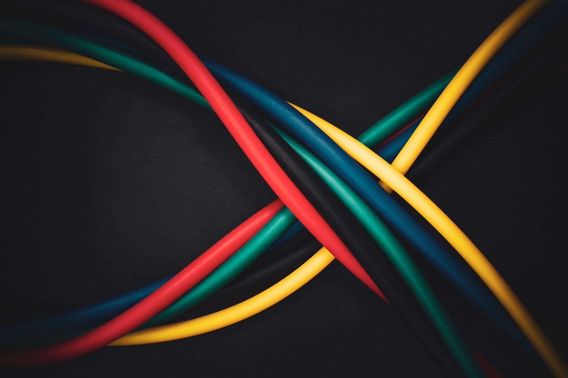 Gekleurde elektriciteitskabels die elkaar kruisen tegen een donkere achtergrond