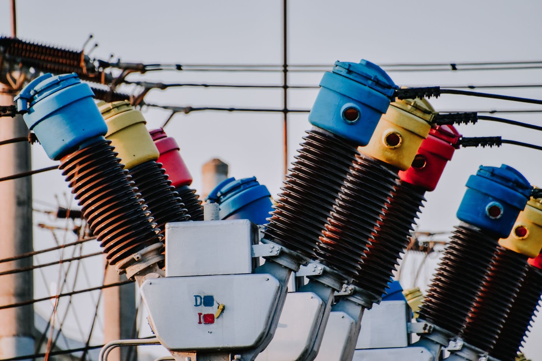 Kleurrijke hoogspanningsisolatoren in een elektriciteitsstation tegen een bewolkte lucht