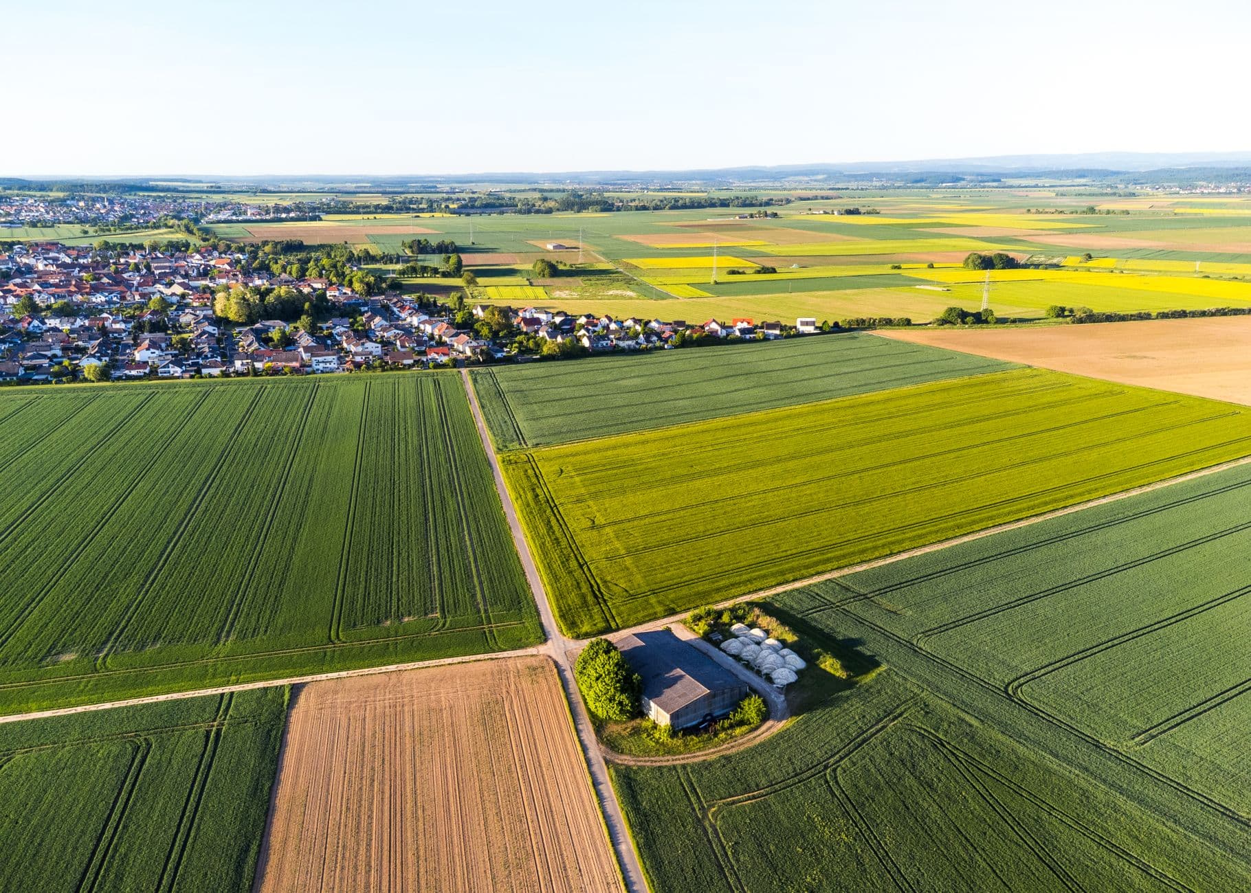 Luchtbeeld van akkers en graanvelden rond een dorp met rode daken