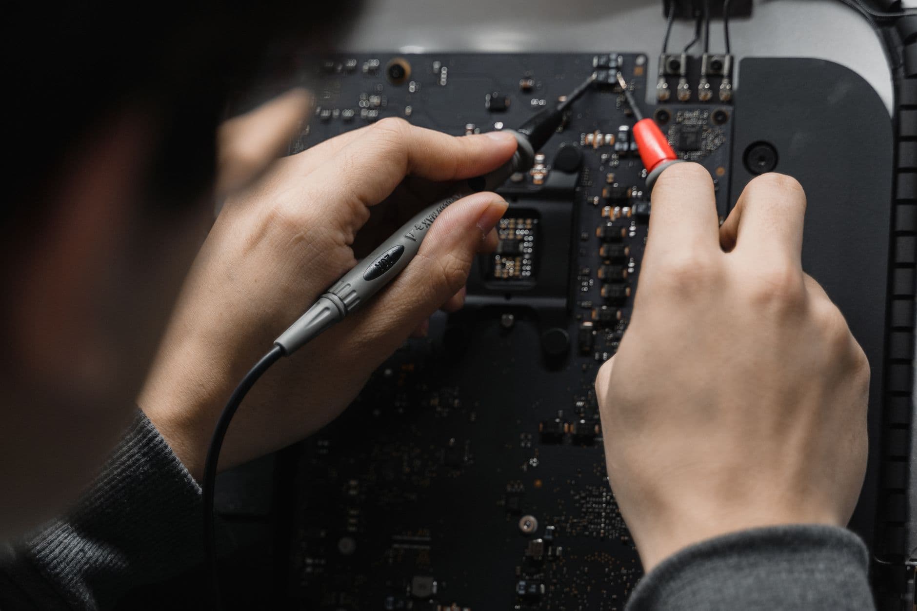 Handen meten met testpennen op een elektronische printplaat