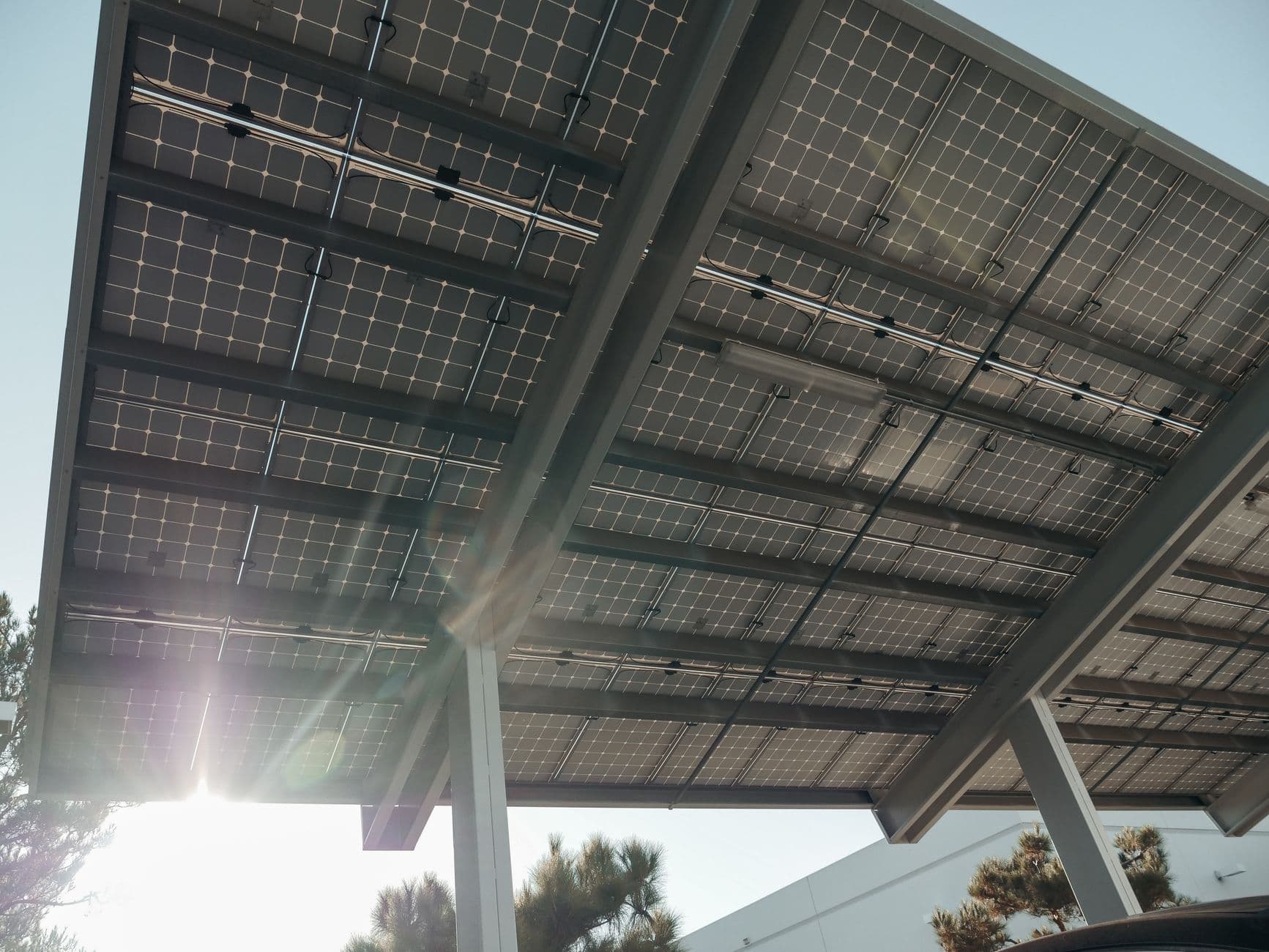 Onderkant van een carport met zonnepanelen, met zonlicht dat tussen de panelen door valt