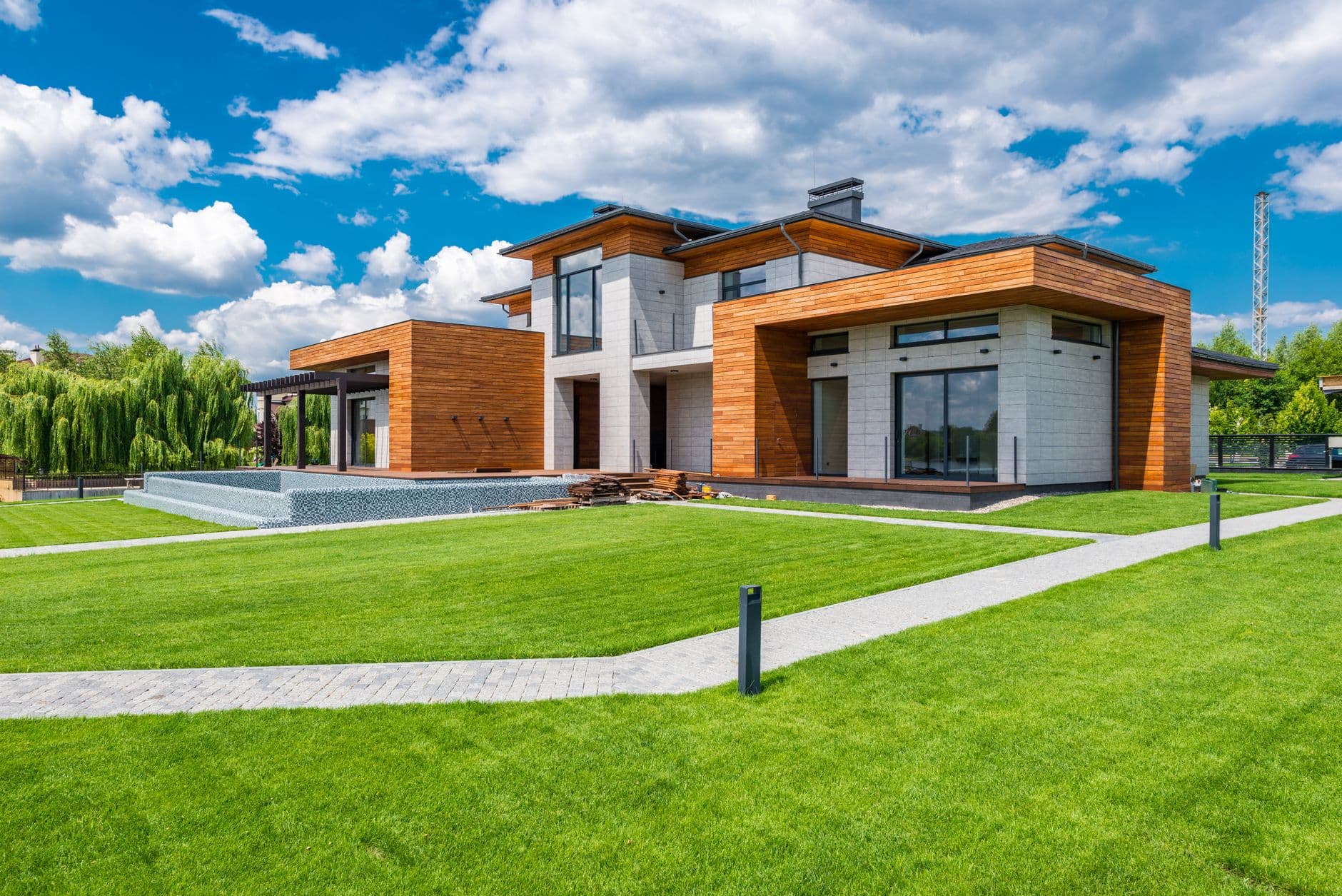 Moderne woning met houten gevelbekleding, lichte steen en een groot gazon onder een blauwe lucht