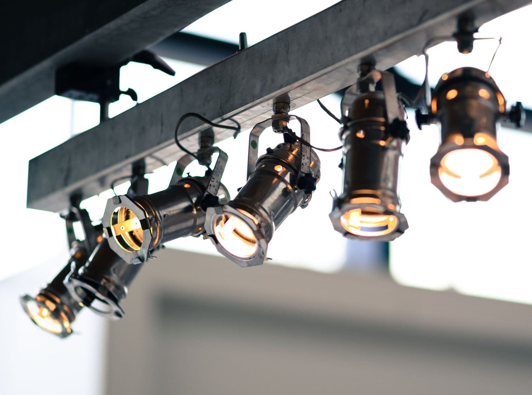 Rij metalen spots aan een plafondrail die warm, gericht licht geven