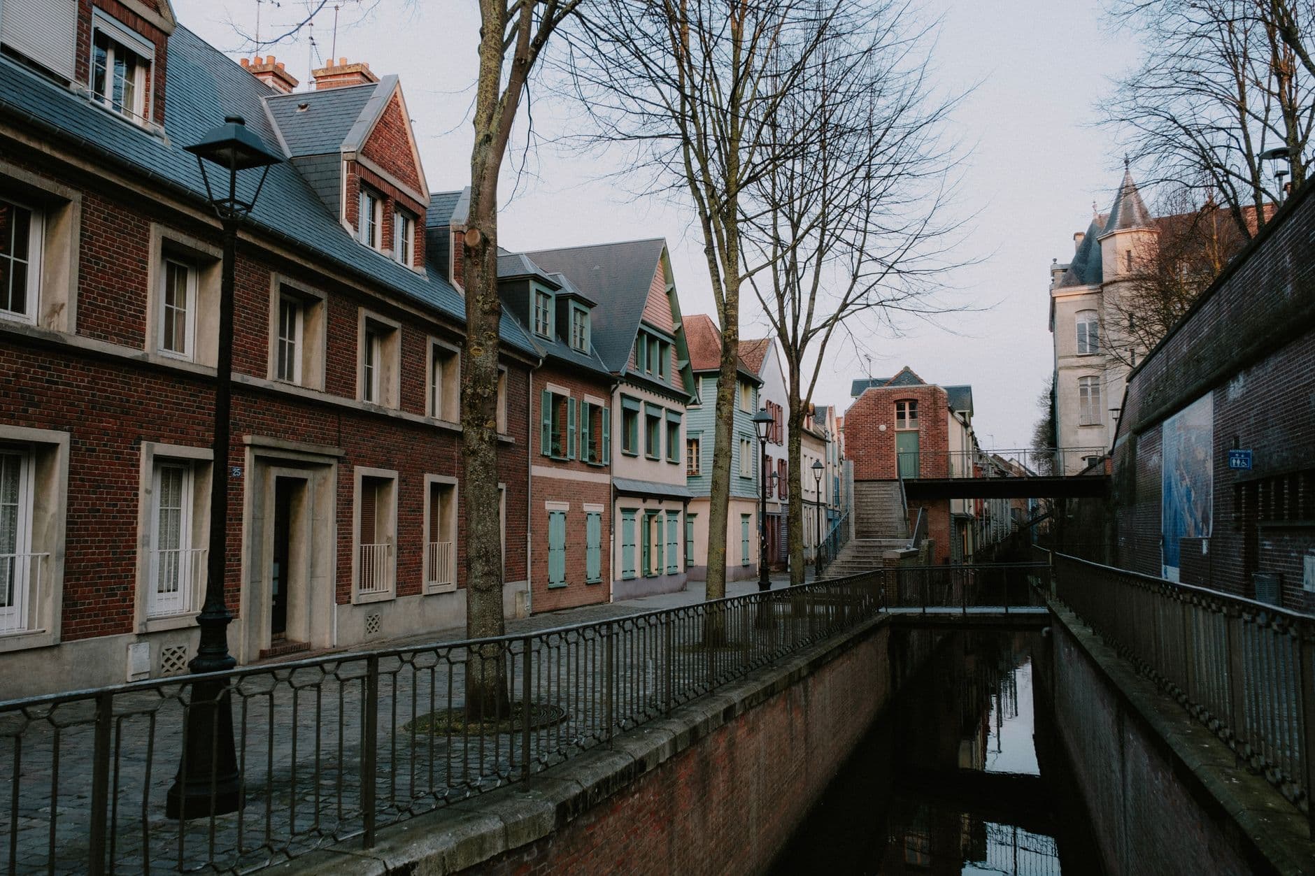 Straat met bakstenen rijhuizen langs een smalle gracht in de schemering