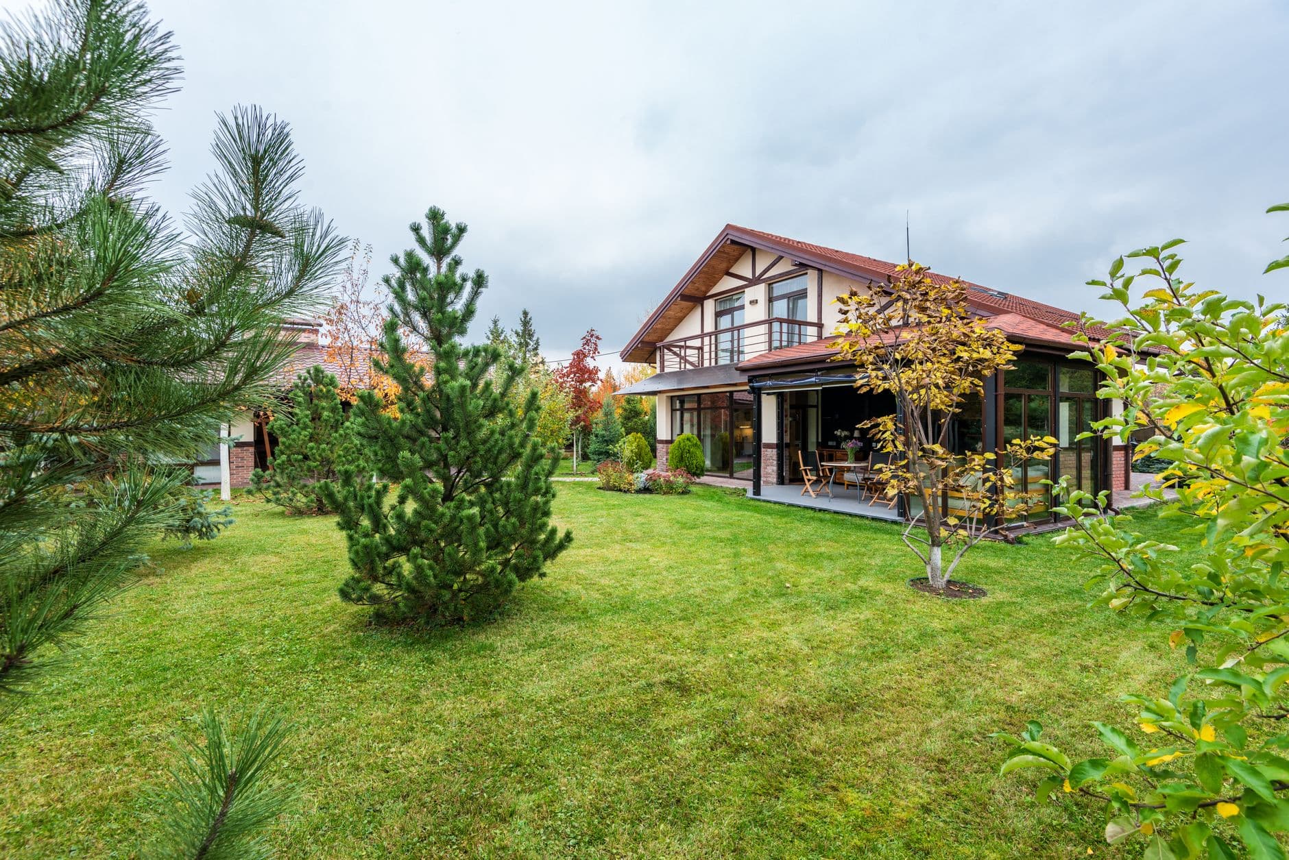 Vrijstaande villa met vakwerkgevel, terras en ruime tuin met dennen en herfstbomen