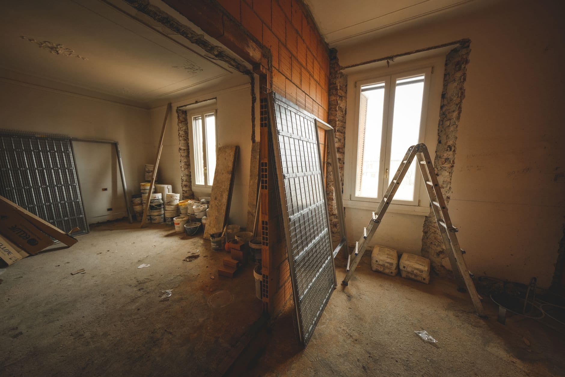 Lege kamer in renovatie met bakstenen muur, ladder en bouwmateriaal voor een hoog raam