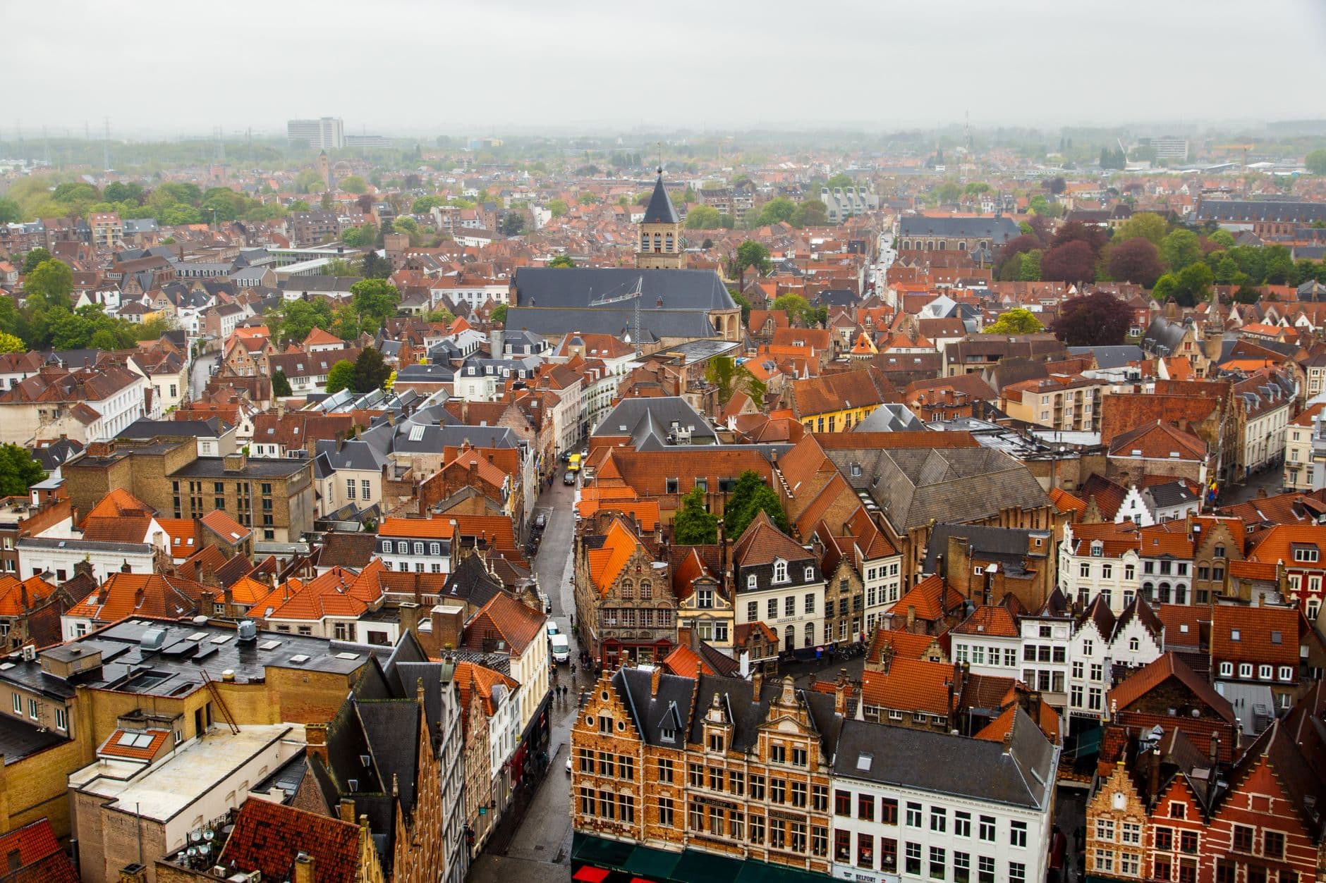 Luchtzicht op een oude stad met rode daken, bakstenen gevels en een kerktoren