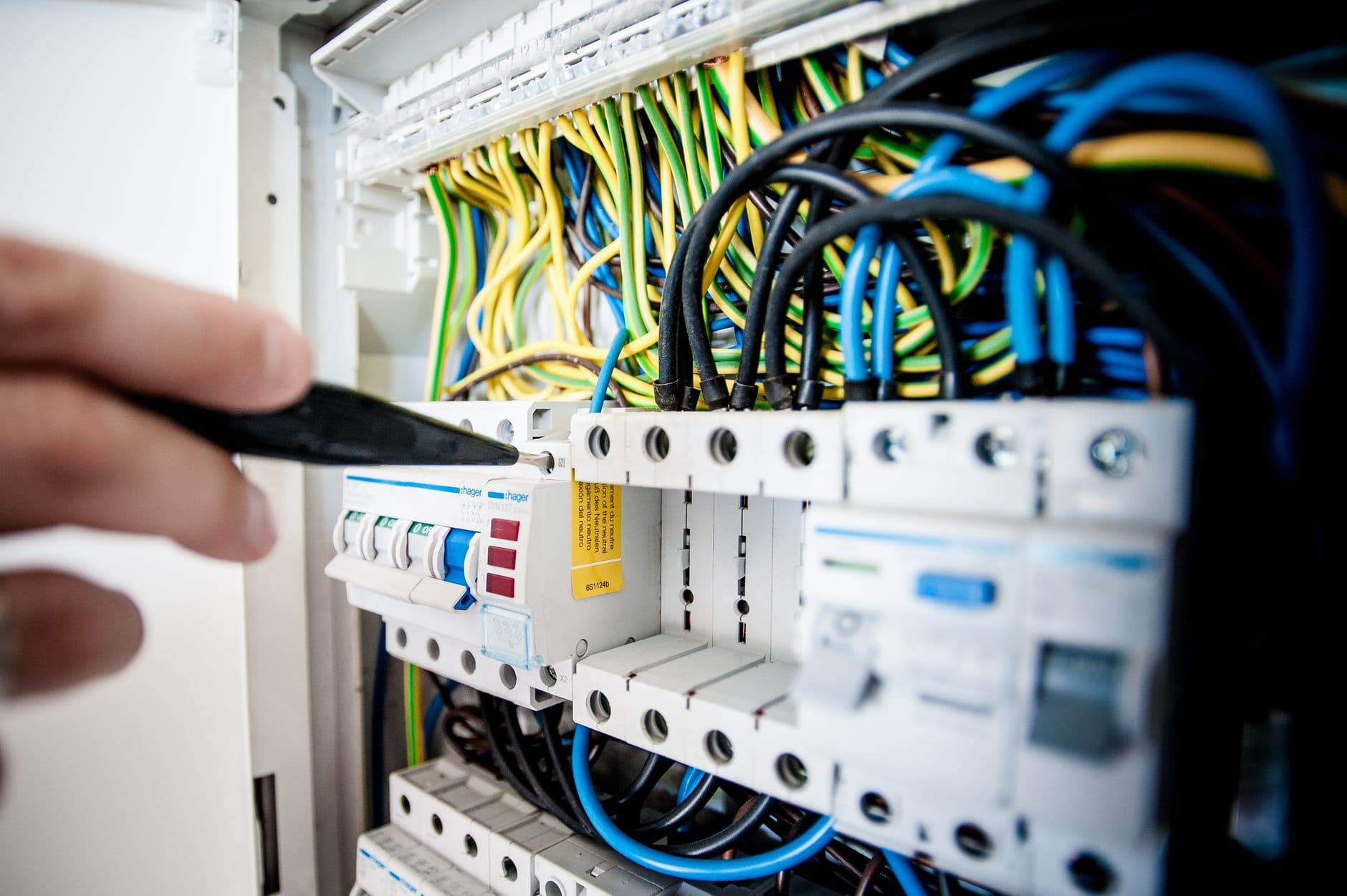 Elektricien controleert automaten en bedrading in een verdeelkast met een schroevendraaier