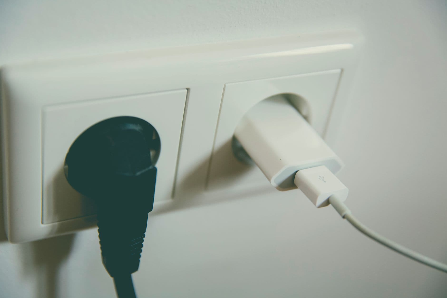Double prise murale blanche avec une fiche et un chargeur de téléphone branchés