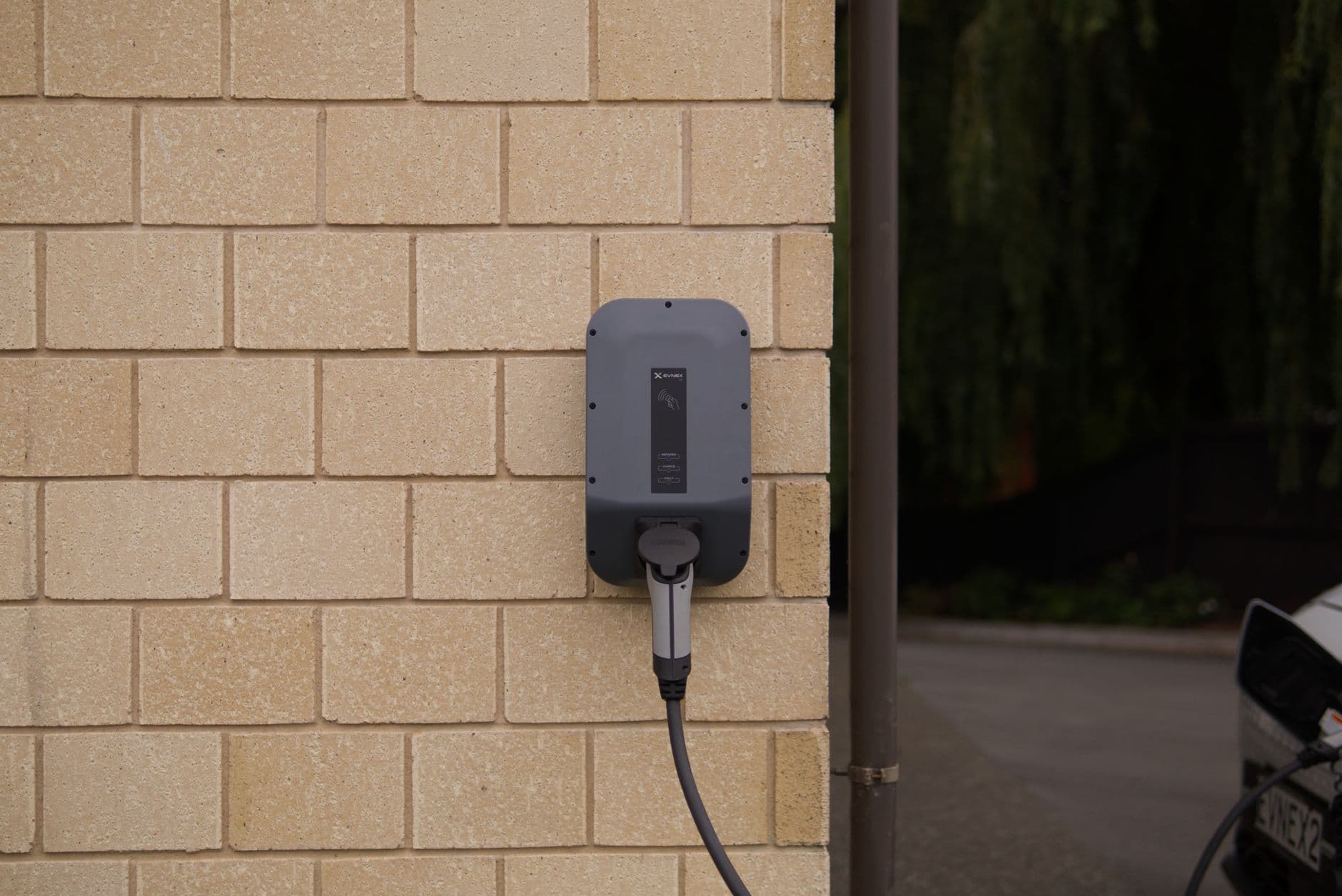 Borne de recharge murale avec câble attaché, fixée sur une façade en briques