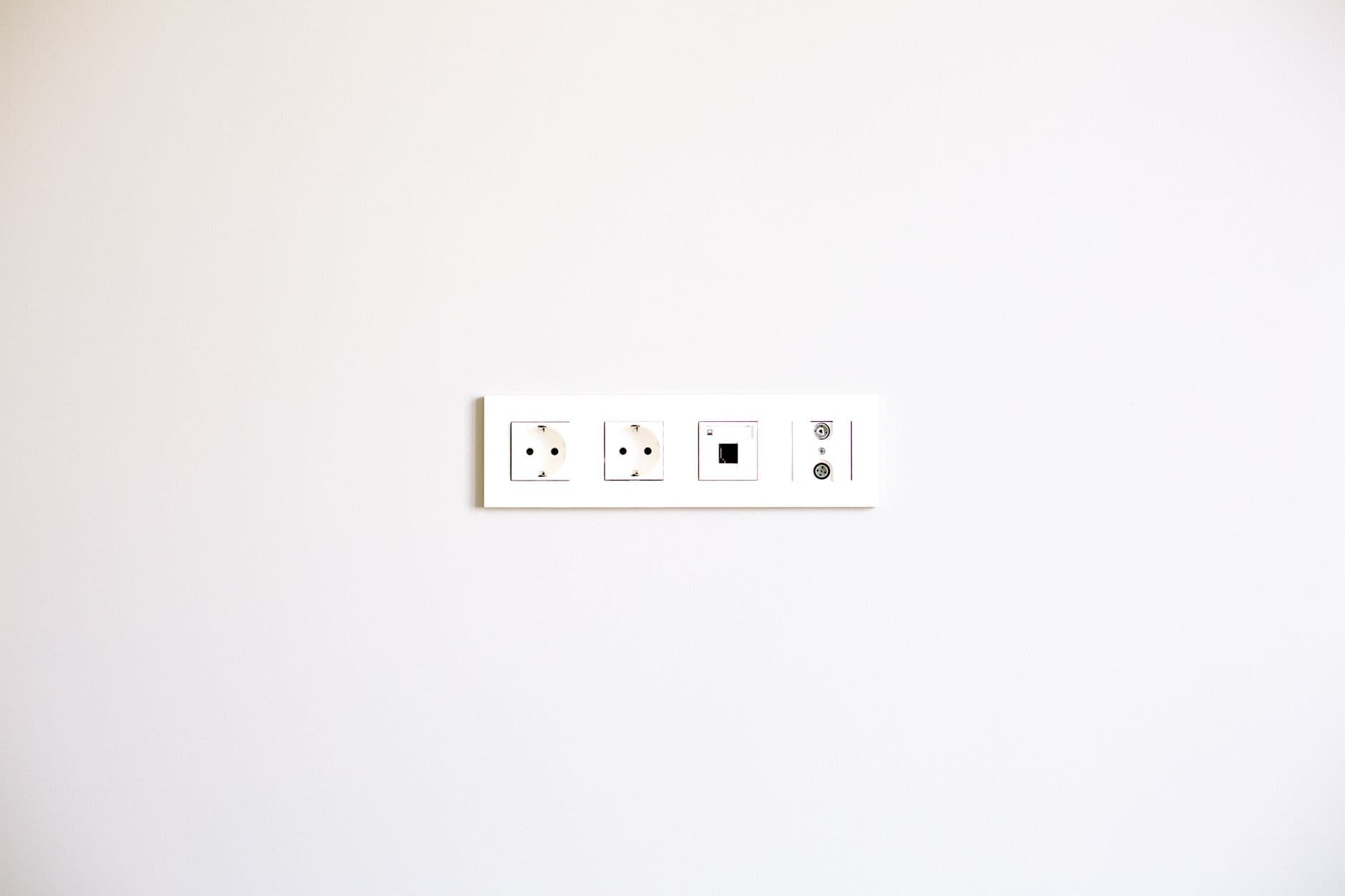 Row of white wall sockets on a white wall