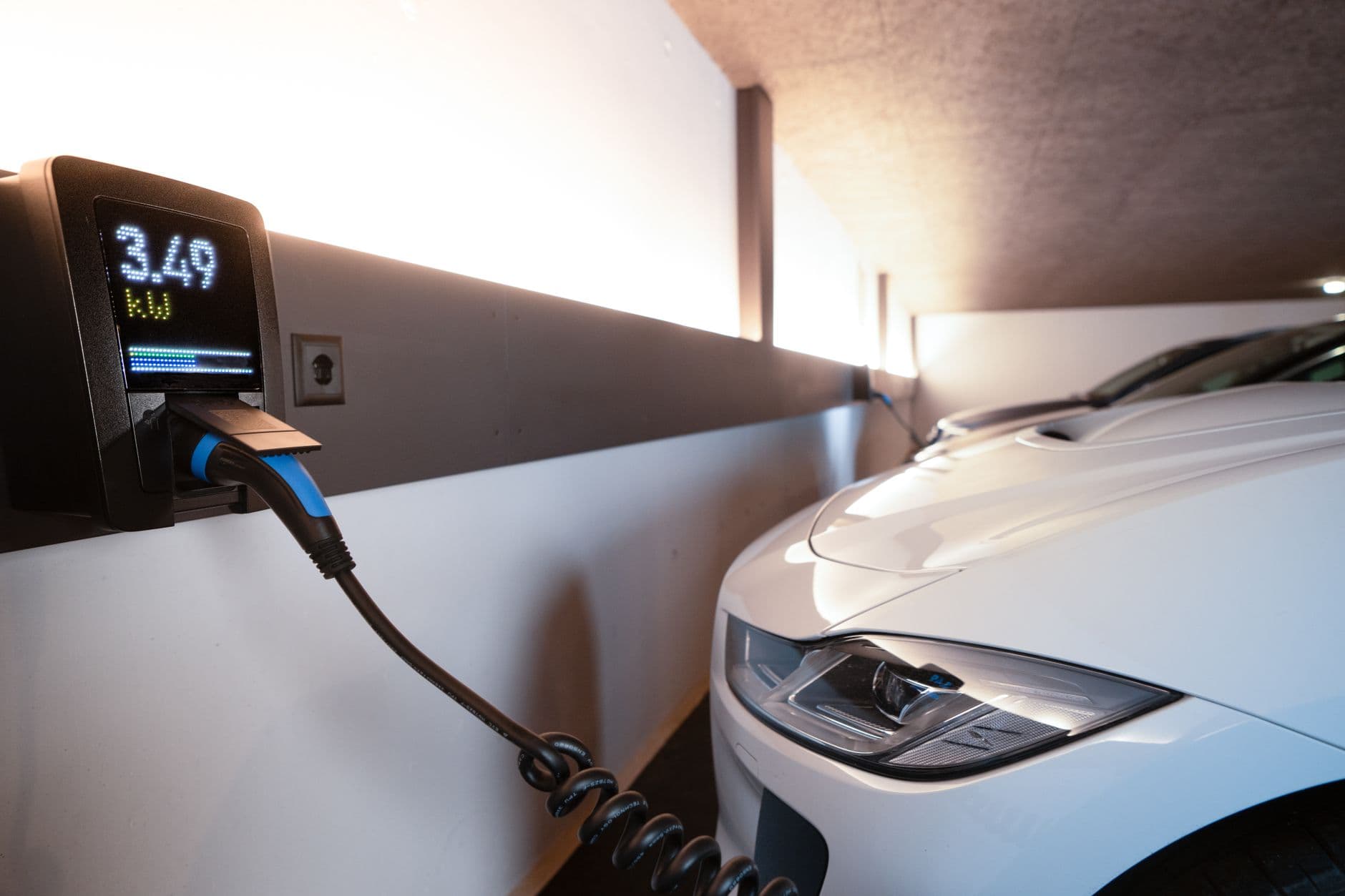 Elektrische auto in een garage aangesloten op een wandlader met display