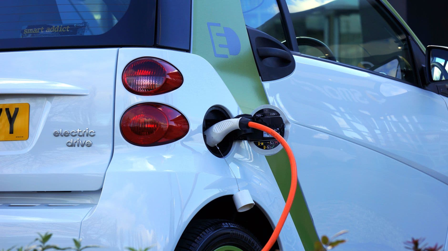 Petite voiture électrique branchée au câble de recharge