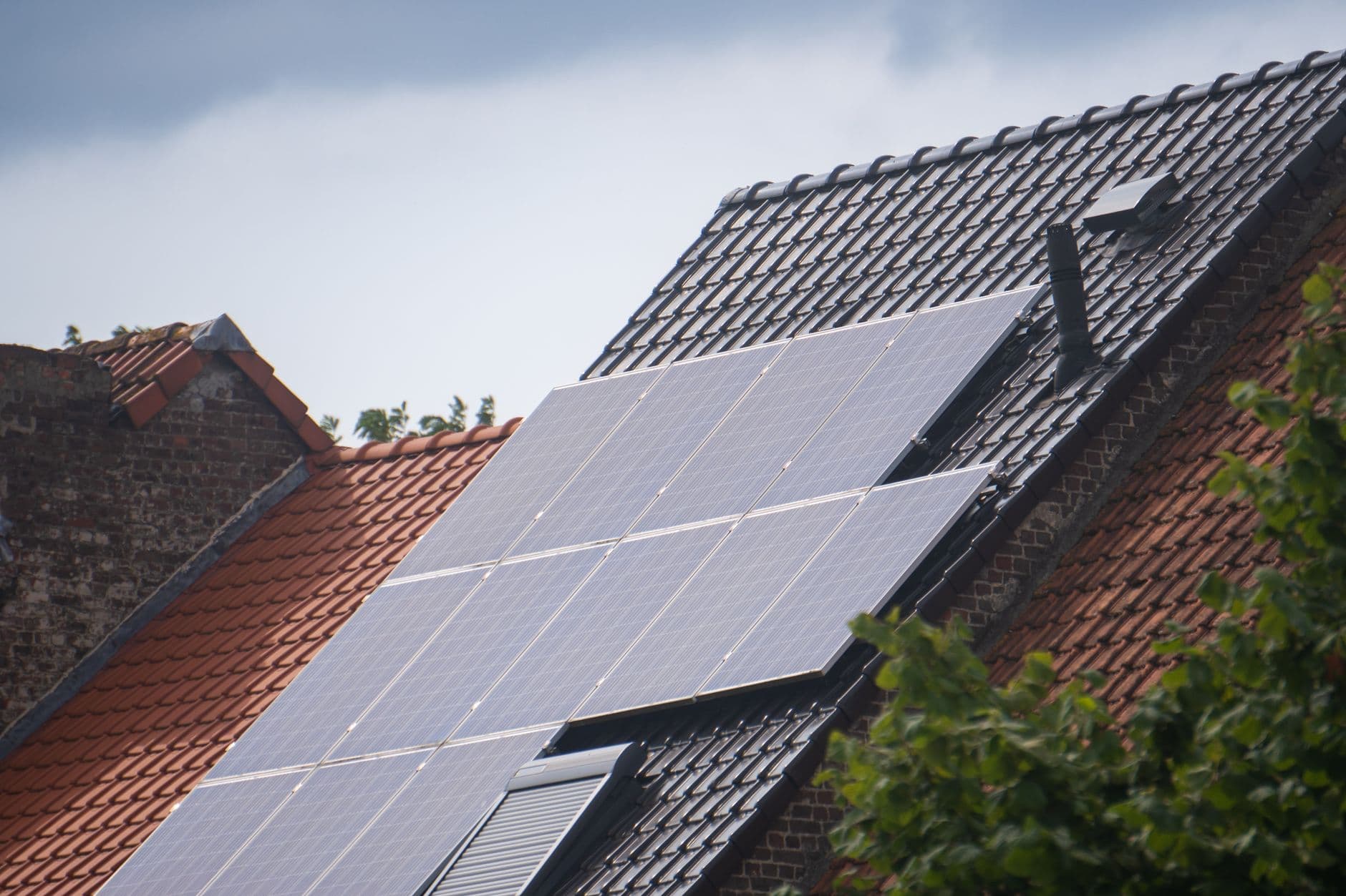 Zonnepanelen op het donkere pannendak van een bakstenen woning