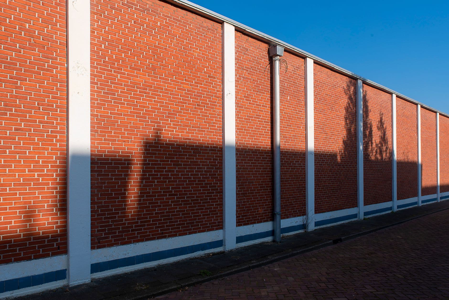 Lange muur van rode baksteen onder een blauwe lucht